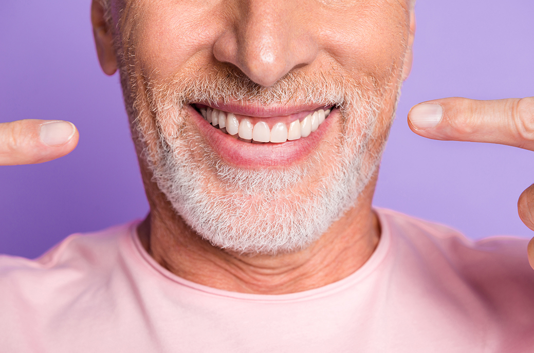 Man pointing to his smile showing his whitened teeth