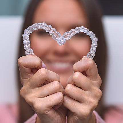 Person holding Invisalign retainers to create a heart shape